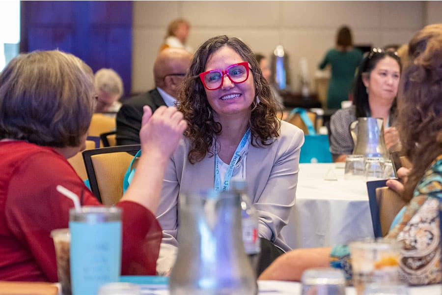 Region 4 Convening Photo of a woman smiling at another woman.